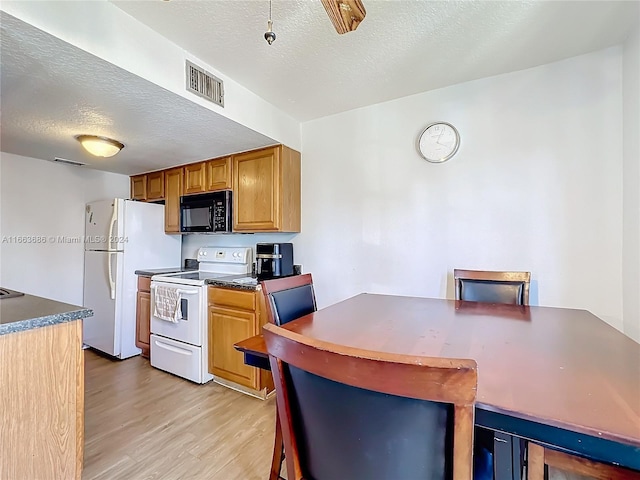 kitchen featuring light hardwood / wood-style flooring, white appliances, and a textured ceiling