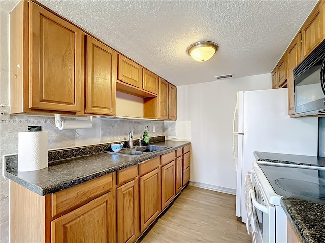 kitchen featuring sink, a textured ceiling, light hardwood / wood-style flooring, white stove, and decorative backsplash