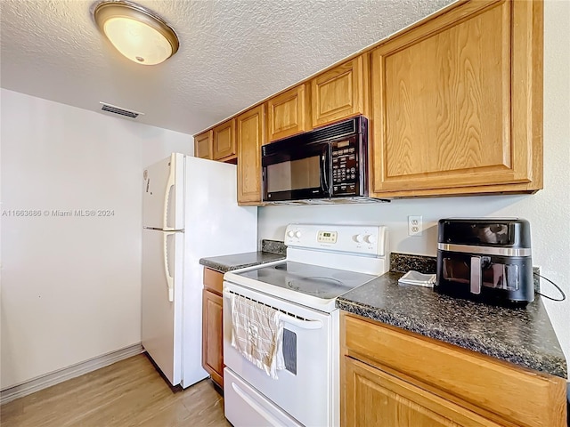 kitchen with light wood-type flooring, white appliances, and a textured ceiling