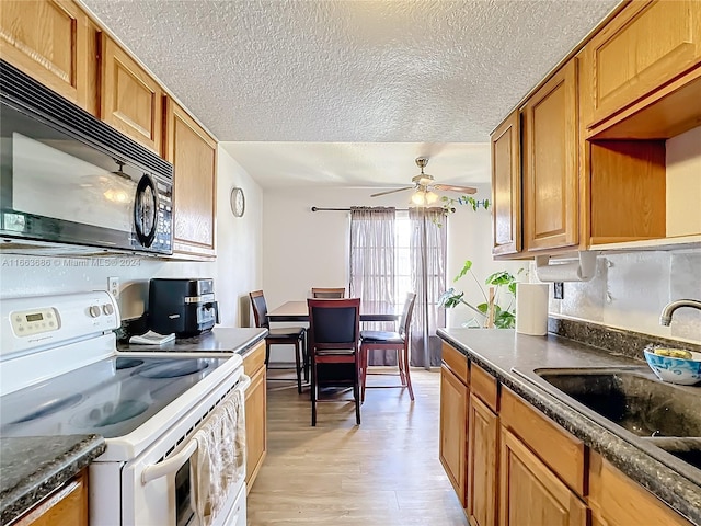 kitchen featuring light wood-type flooring, a textured ceiling, electric range, sink, and ceiling fan