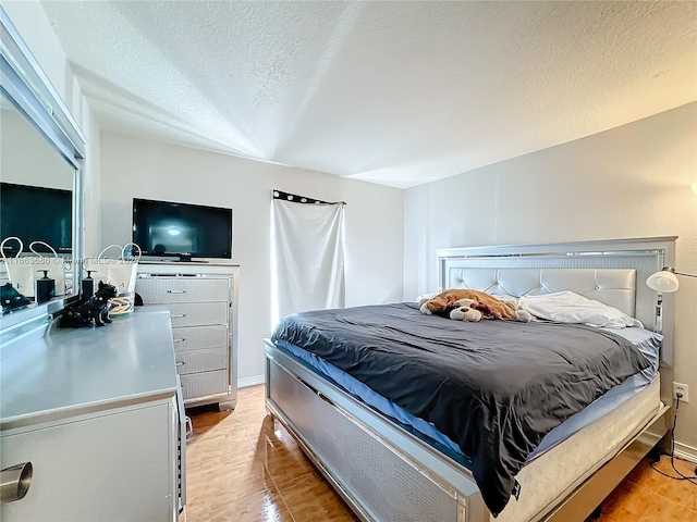 bedroom featuring light hardwood / wood-style flooring and a textured ceiling