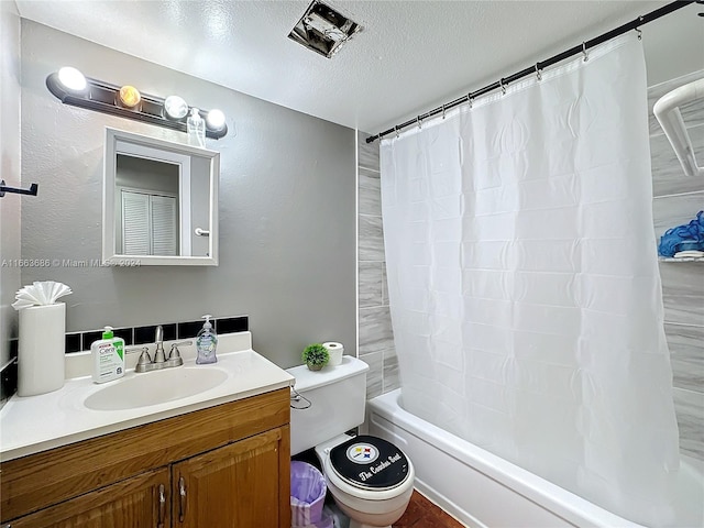 full bathroom featuring a textured ceiling, shower / bath combo, vanity, and toilet