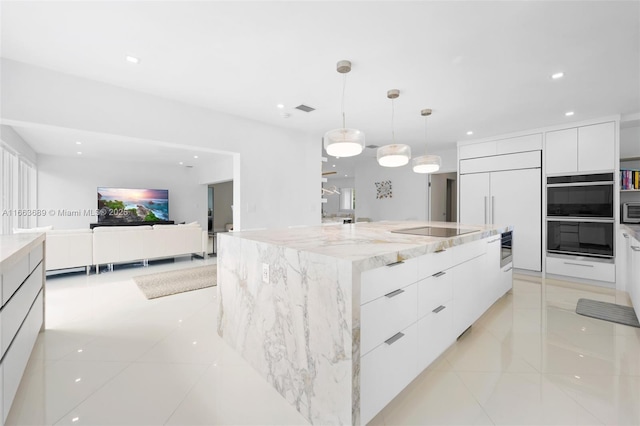 kitchen with pendant lighting, paneled built in fridge, double wall oven, white cabinetry, and a large island with sink