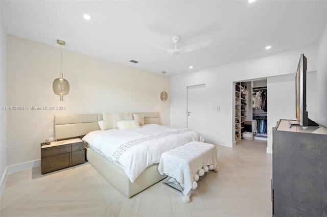 bedroom with a walk in closet, a closet, ceiling fan, and light parquet flooring