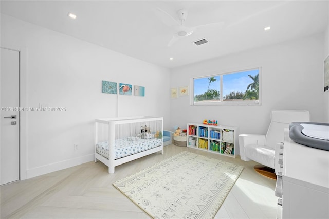 bedroom featuring ceiling fan, light parquet floors, and a nursery area