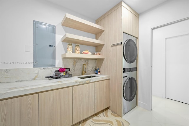 laundry room with electric panel, stacked washing maching and dryer, light tile patterned floors, and sink