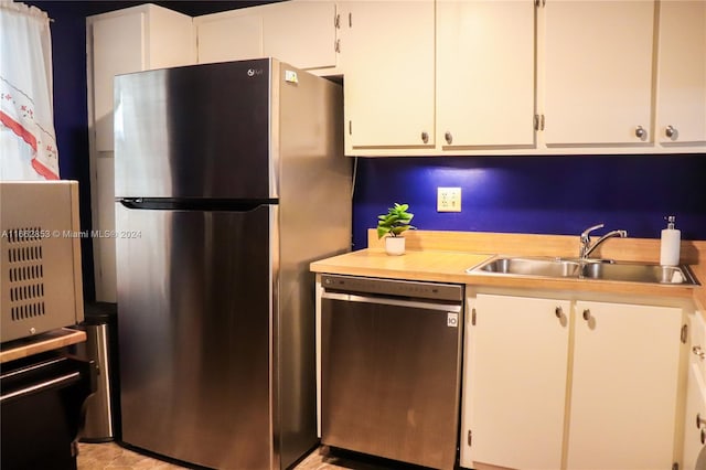 kitchen with stainless steel appliances, sink, and white cabinetry