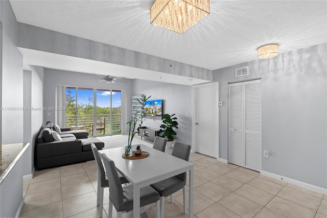 tiled dining area with a textured ceiling and ceiling fan