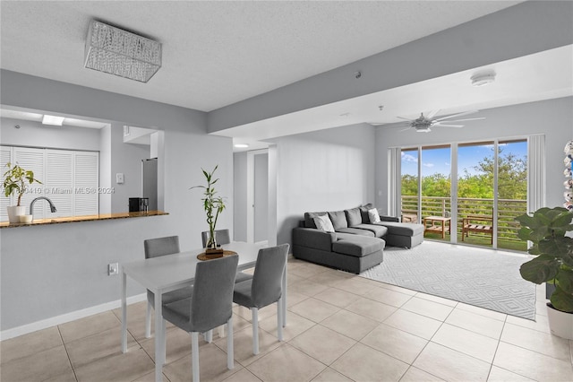 tiled dining area featuring a textured ceiling, sink, and ceiling fan