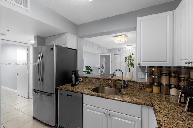 kitchen with dark stone counters, sink, white cabinets, appliances with stainless steel finishes, and a textured ceiling