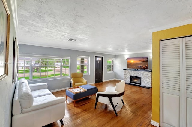 living room with ornamental molding, wood-type flooring, a textured ceiling, and a fireplace