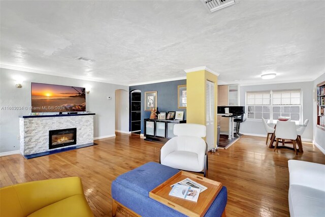 540 NE 142nd St, North Miami, FL 33161 - living room featuring arched walkways, wood finished floors, crown molding, a stone fireplace, and baseboards
