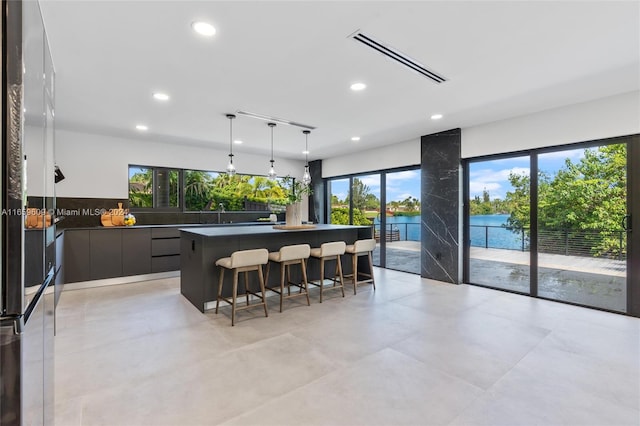 kitchen featuring high end refrigerator, hanging light fixtures, a water view, and a breakfast bar area