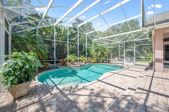 view of pool featuring glass enclosure and a patio