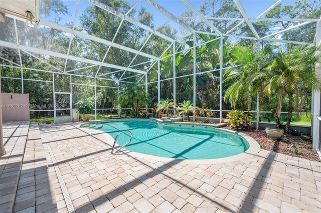 view of pool featuring glass enclosure and a patio