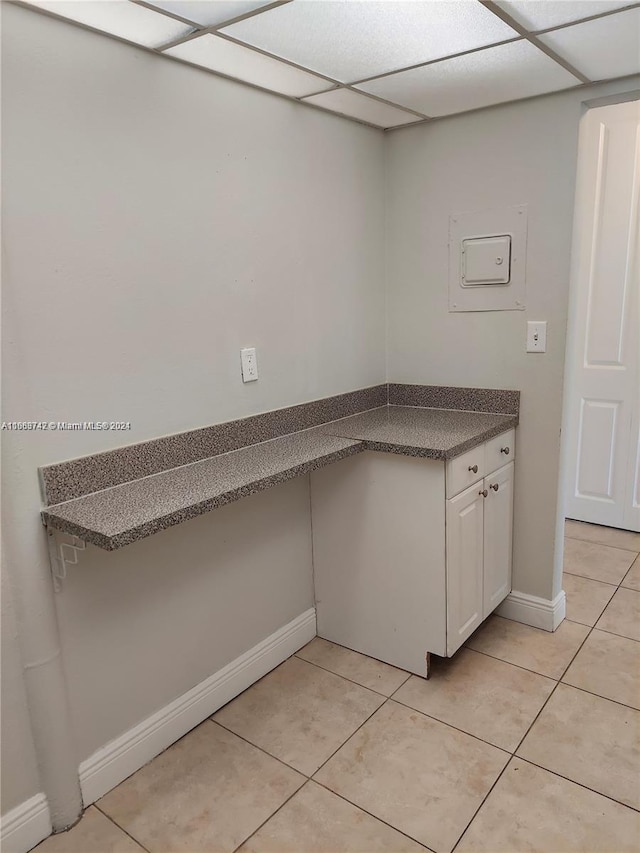 kitchen featuring light tile patterned flooring, a paneled ceiling, and white cabinetry