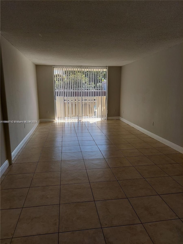 spare room with a textured ceiling and tile patterned flooring