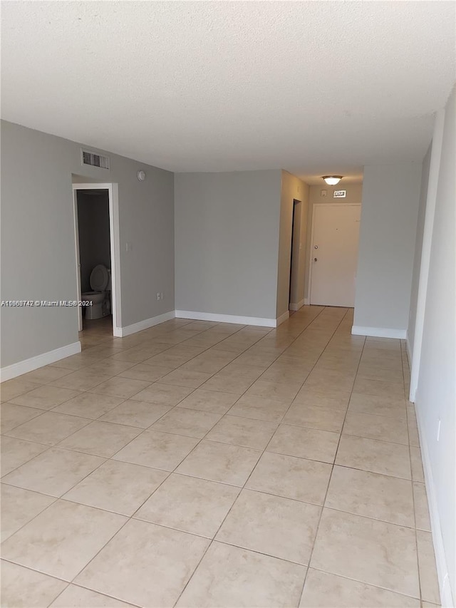 spare room featuring a textured ceiling and light tile patterned floors