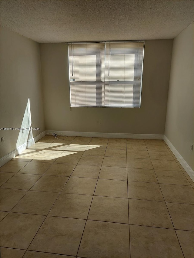 tiled empty room featuring a textured ceiling