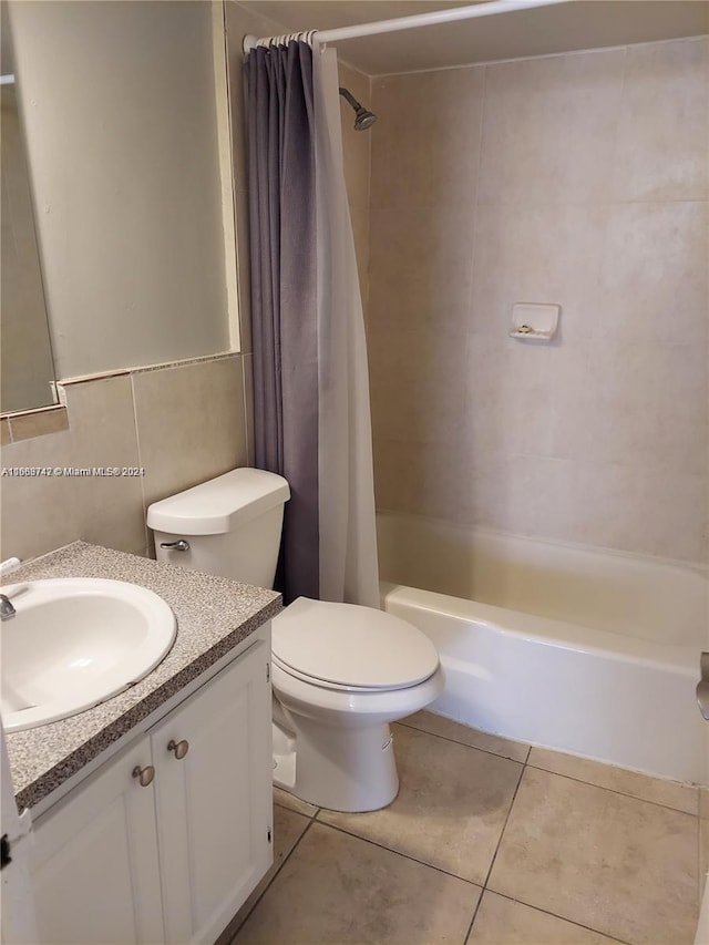 full bathroom with tile walls, vanity, shower / tub combo with curtain, toilet, and tile patterned floors