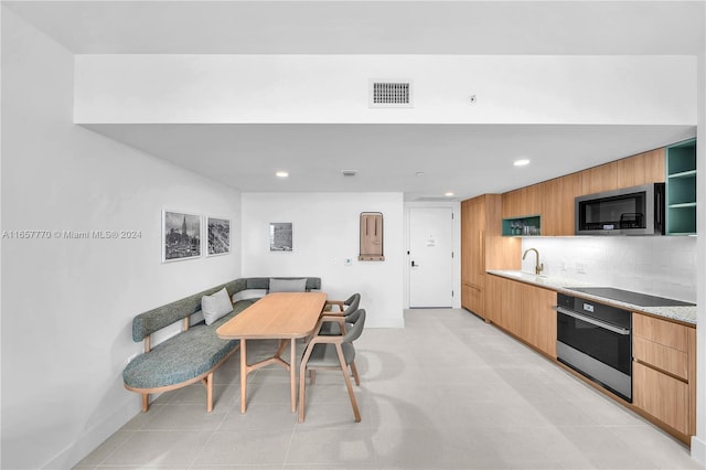 kitchen with stainless steel appliances, backsplash, light tile patterned floors, and sink