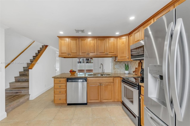 kitchen with light tile patterned floors, sink, stone counters, stainless steel appliances, and decorative backsplash