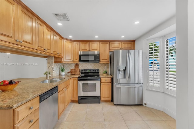 kitchen featuring light stone counters, appliances with stainless steel finishes, light tile patterned floors, and sink