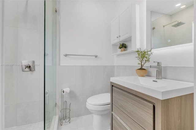 bathroom with tile walls, a shower with shower door, vanity, toilet, and tile patterned floors