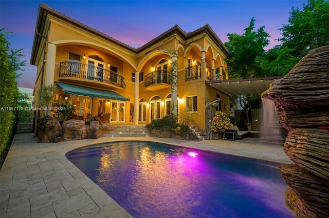 pool at dusk featuring a patio area