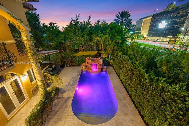 pool at dusk featuring a patio area