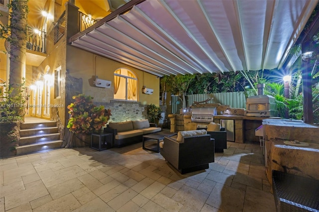 view of patio / terrace with a balcony, an outdoor living space, a grill, and exterior kitchen