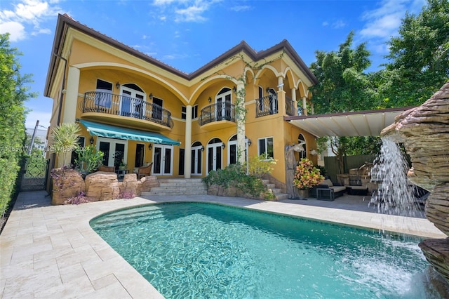 back of house with a balcony, a patio, an outdoor hangout area, and pool water feature