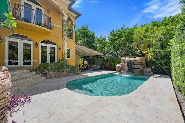 view of swimming pool with french doors, a patio, and pool water feature