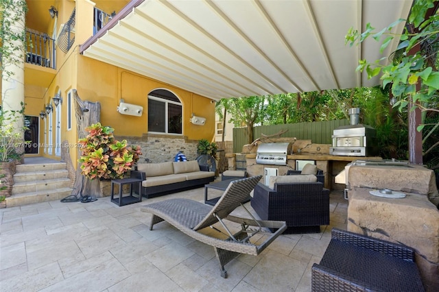 view of patio with a grill, a balcony, outdoor lounge area, and exterior kitchen