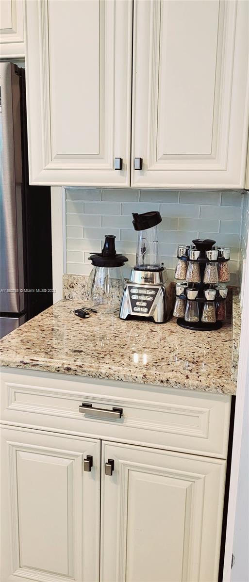 interior space featuring white cabinets, light stone countertops, and tasteful backsplash