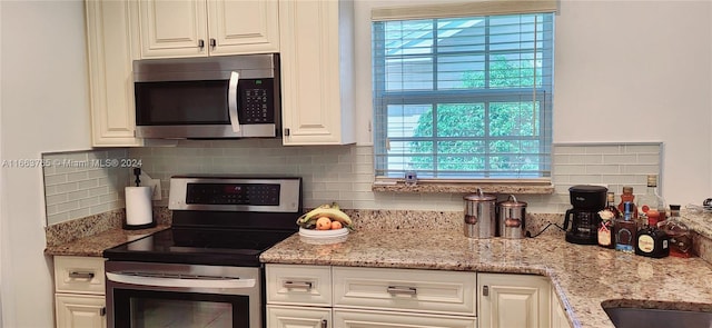 kitchen with white cabinets, appliances with stainless steel finishes, and backsplash