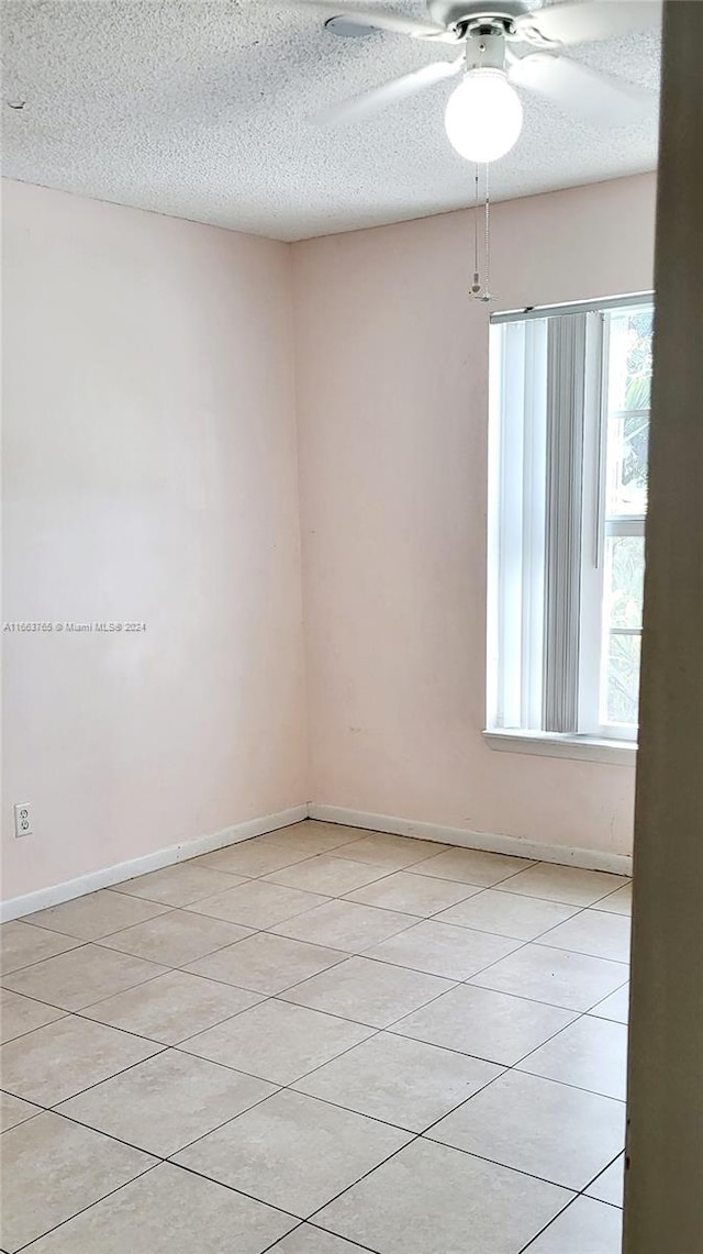 spare room featuring ceiling fan, a textured ceiling, and light tile patterned flooring