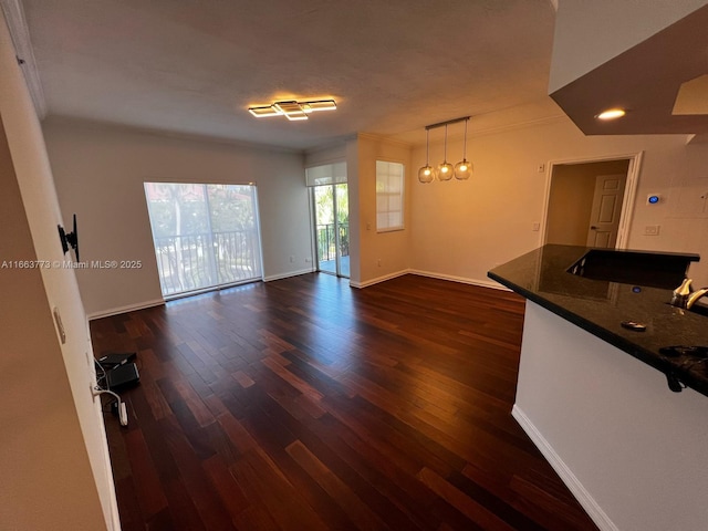 unfurnished living room featuring dark hardwood / wood-style flooring and ornamental molding