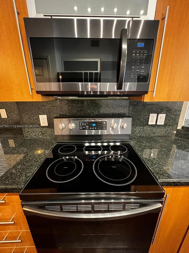 details featuring dark stone countertops, backsplash, and appliances with stainless steel finishes