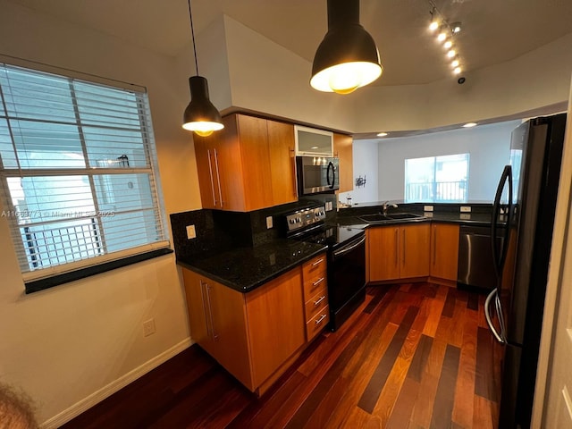 kitchen featuring appliances with stainless steel finishes, dark hardwood / wood-style flooring, sink, decorative light fixtures, and dark stone countertops