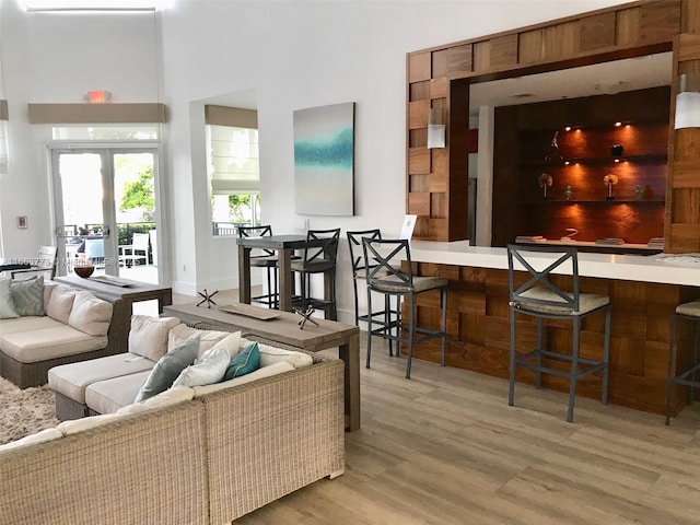 living room with french doors, a towering ceiling, and light hardwood / wood-style flooring