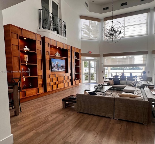 living room featuring a high ceiling, an inviting chandelier, french doors, and wood-type flooring