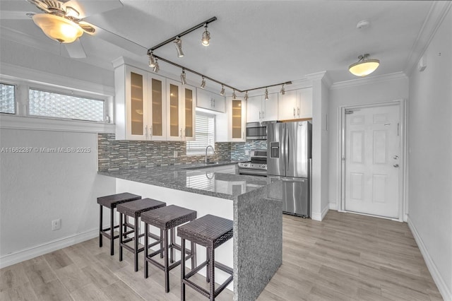 kitchen featuring a breakfast bar area, stainless steel appliances, decorative backsplash, a sink, and a peninsula