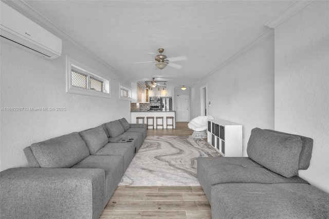 living area with light wood finished floors, ornamental molding, and a wall mounted AC