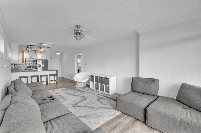 living room with light wood finished floors, a ceiling fan, and crown molding