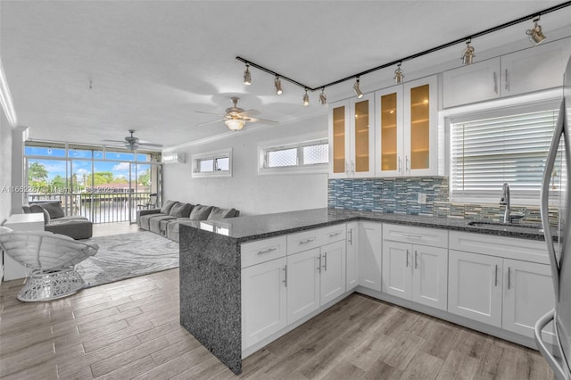 kitchen with white cabinets, a sink, a peninsula, and decorative backsplash