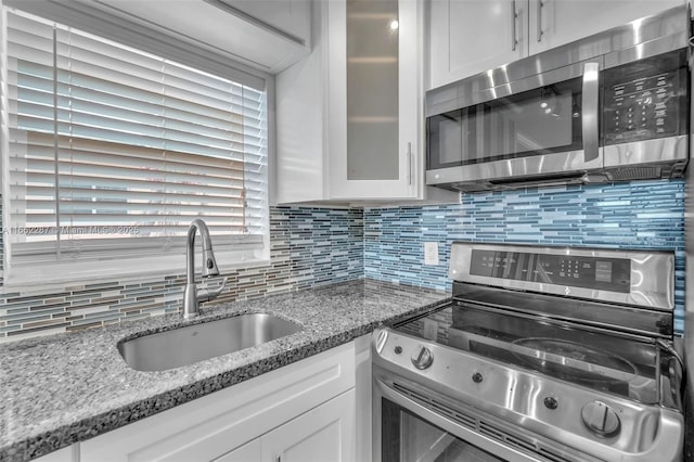 kitchen featuring stainless steel appliances, tasteful backsplash, a sink, and white cabinets