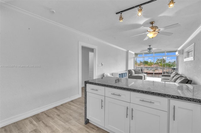 kitchen featuring light wood-type flooring, ornamental molding, white cabinets, and dark stone countertops