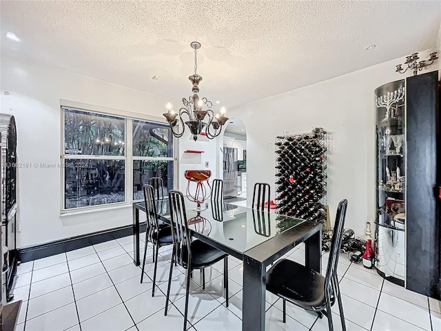 dining room featuring an inviting chandelier, a textured ceiling, and light tile patterned flooring