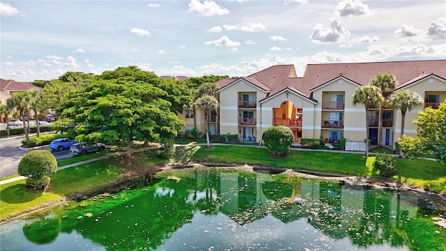 exterior space with a water view, a balcony, and a front yard